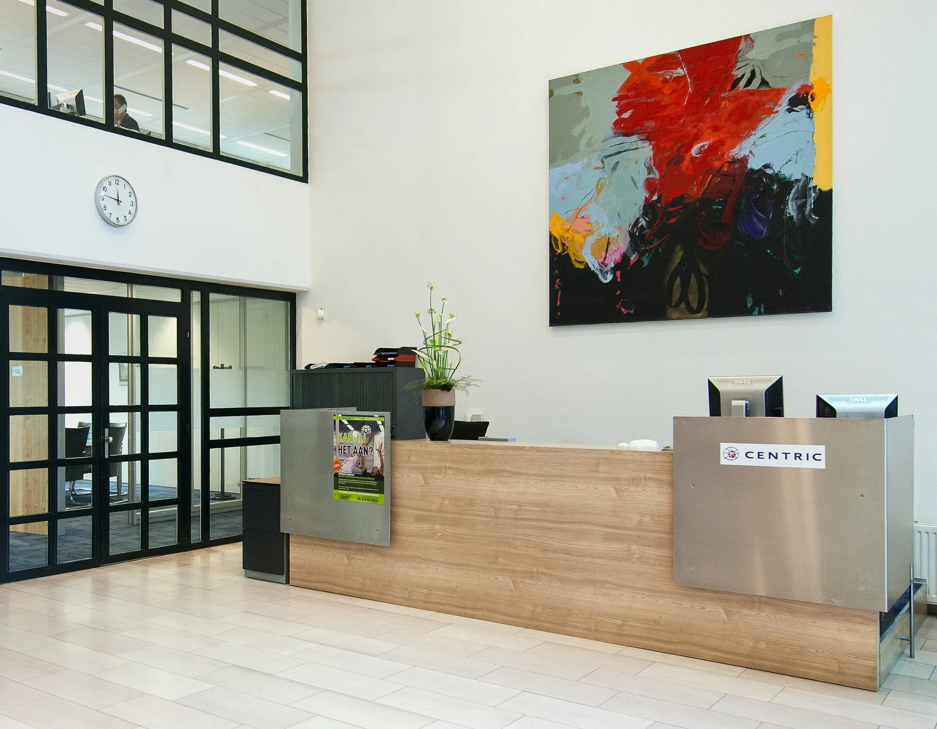 Een strakke en moderne receptie met een groot schilderij aan de muur, een houten balie en een glazen deur naar de vergaderruimte.