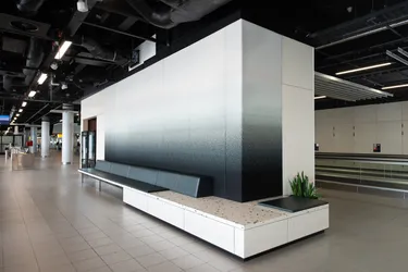 Een ruime, moderne wachtruimte in een kantoor met een lange bank en een grote schermwand, perfect voor een professionele omgeving.