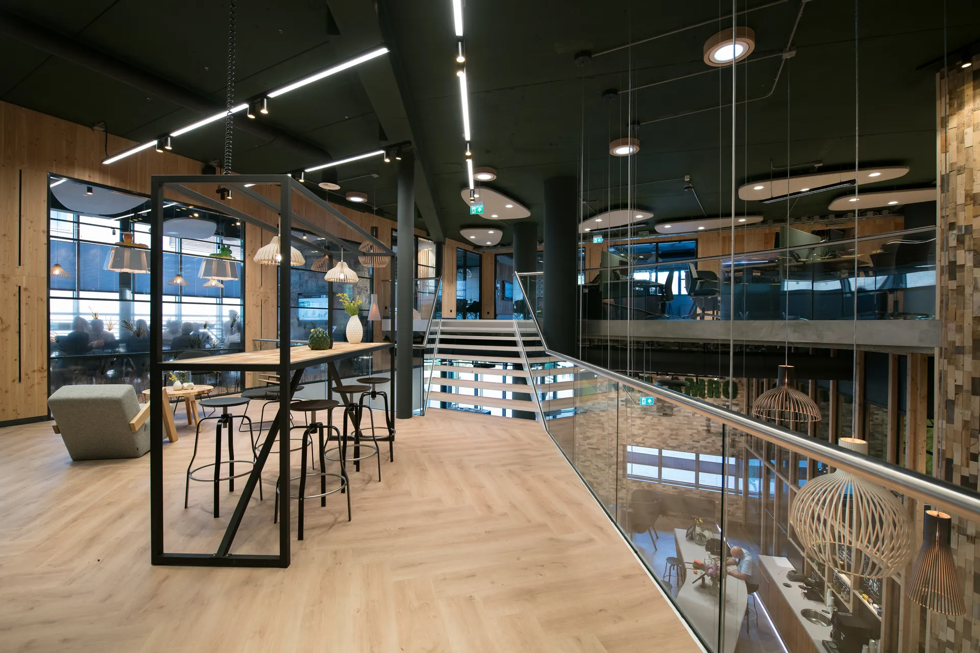 Een moderne kantoorruimte met een grote open ruimte, een centrale tafel met stoelen, een zithoek en een glazen wand met uitzicht over de stad.