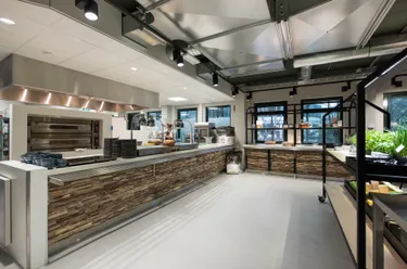 Een moderne keuken in industriële stijl met een lang roestvrijstalen aanrecht en een groot, industrieel fornuis.