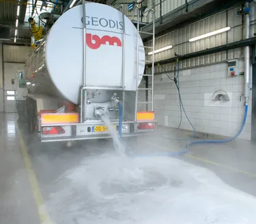 Een grote tankwagen in een loods of bedrijfshal, die klaargemaakt wordt voor transport.