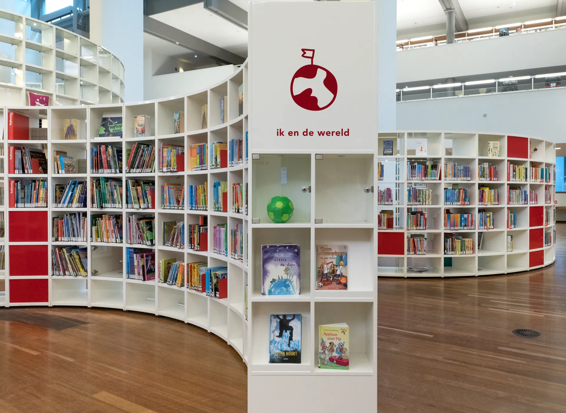 Een moderne bibliotheek met een grote ronde gebogen boekenkastwand die een centrale asymmetrische kamer omsluit.