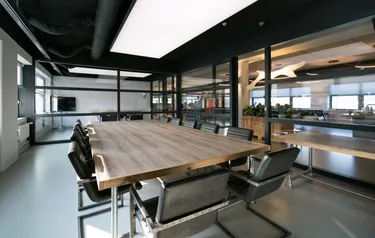 Een moderne vergaderruimte op een kantoor met een grote houten tafel en zwarte stoelen, perfect voor groepspresentaties.