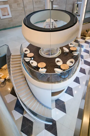 Een moderne open ontvangsthal van een bedrijfspand of kantoor met opvallend witte trappen die overlappen in de ruimte.