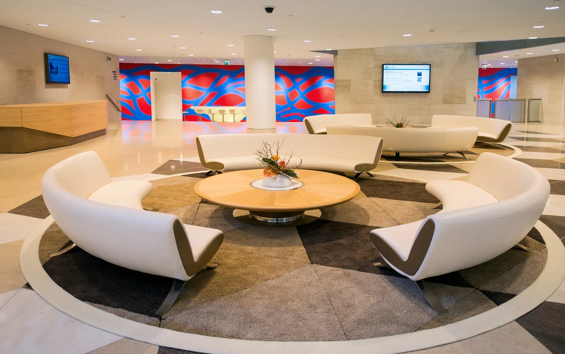 Een speciaal afgeronde moderne wachtkamer binnen een kantoor voorzien van abstracte kleurrijke kunst aan de gebogen muur.